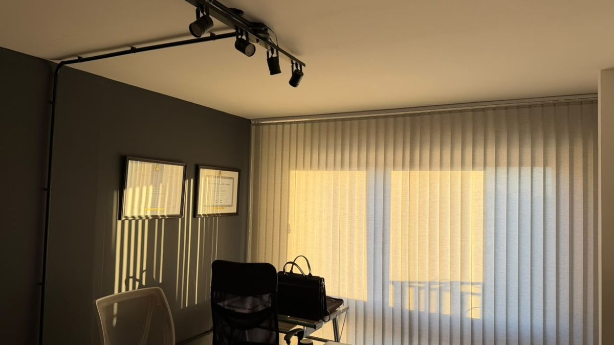 Oficina del estudio con escritorio, diplomas en la pared y luz de la tarde entrando por la cortina
